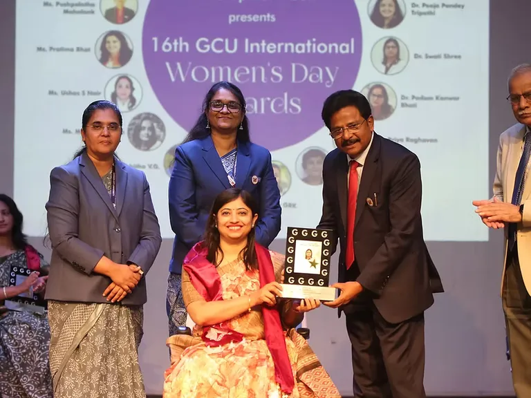 People standing together with an award at a Garden City University event.